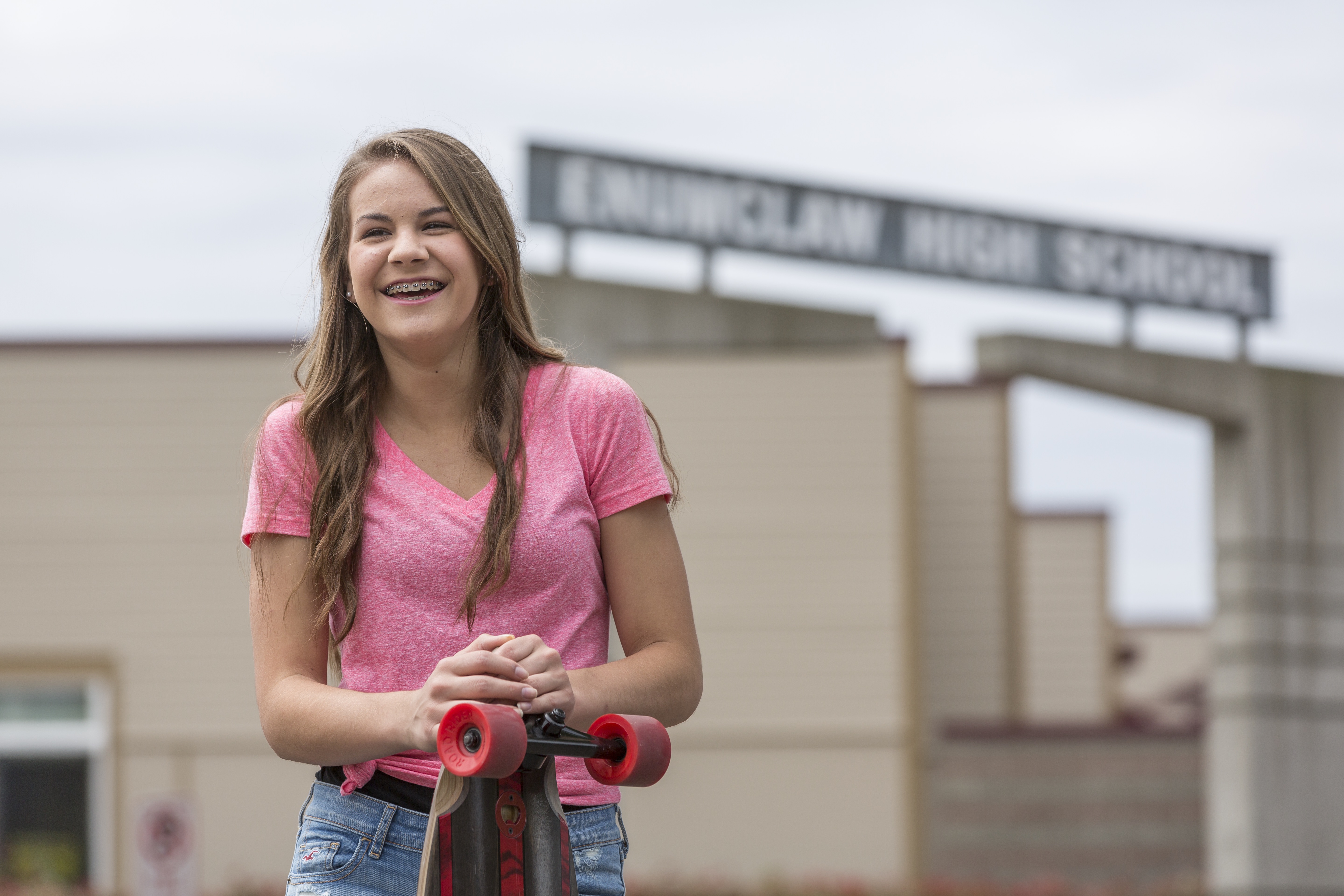 teenage girl smiling and holding a skateboard