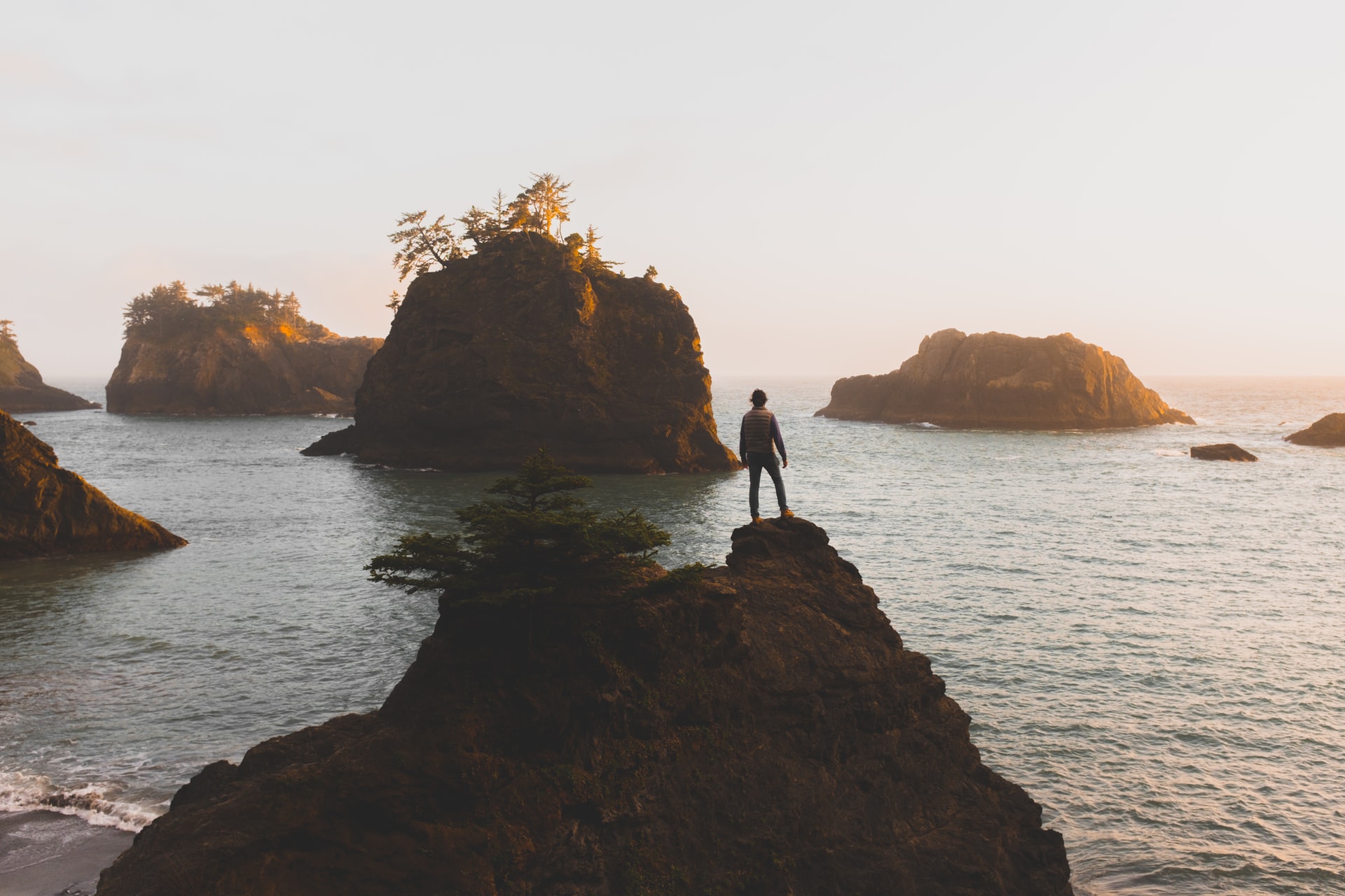 person standing on cliff looking at water